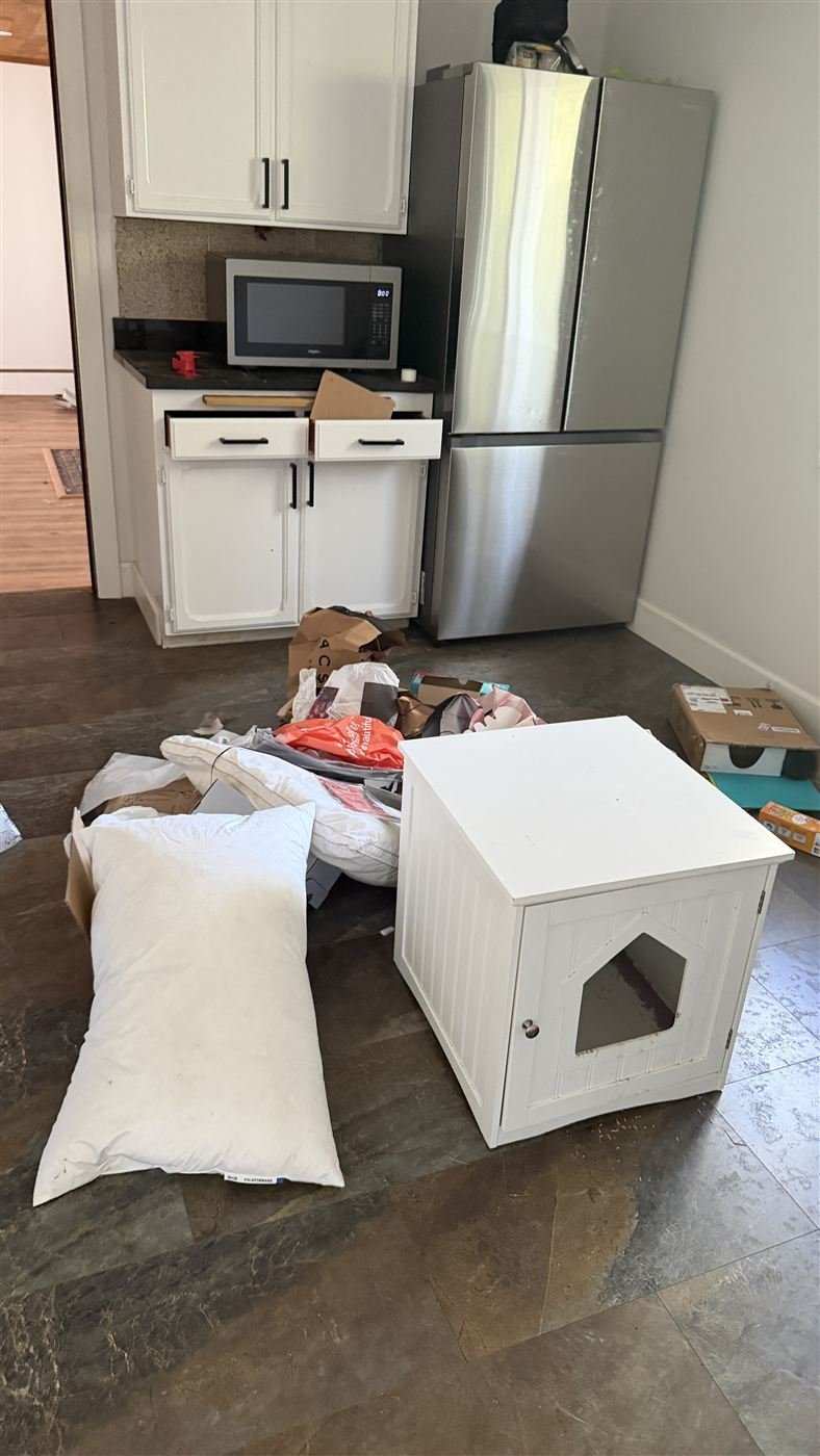 Kitchen before junk removal, floor covered in clutter