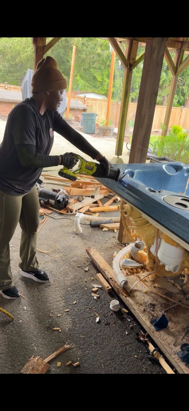 Crew cutting apart a hot tub shell during removal in Edmonds